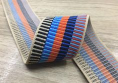 an orange, blue and black striped ribbon on a wooden table with wood grained surface