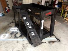 a dog house made out of pallets with paw prints on the side and inside