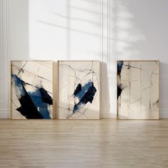 three abstract paintings are displayed on the wall in an empty room with hard wood flooring