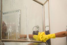 a person in yellow gloves cleaning a mirror