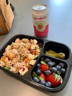 a lunch tray with fruit, pasta and yogurt next to a can of soda