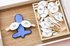 a wooden box filled with cut out letters next to a toy airplane on top of a table