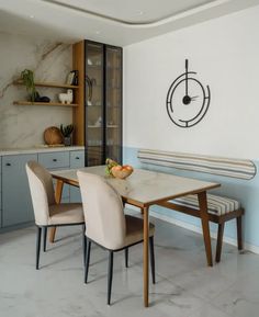 a dining room table with two chairs and a clock on the wall above it,