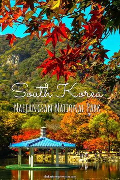 a gazebo sitting in the middle of a lake surrounded by trees with red leaves