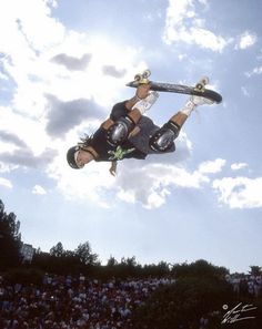 a man flying through the air while riding a skateboard in front of a crowd