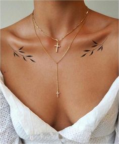 a woman with tattoos on her chest wearing a cross and chain choker necklace in gold