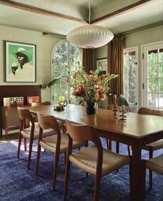 a dining room table with chairs and a vase filled with flowers on top of it