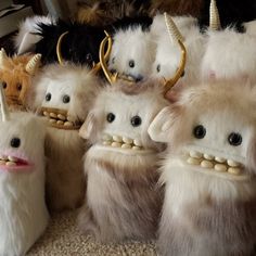 there are many stuffed animals with horns and teeth on their heads, all lined up together