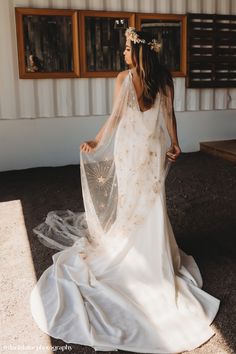 a woman in a wedding dress is standing outside with her back to the camera and looking off into the distance