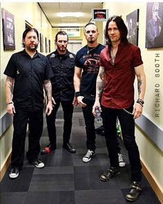 three men are standing in an office hallway