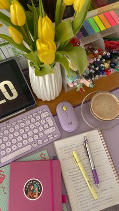 a desk with a keyboard, notebook and flowers