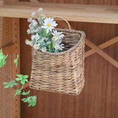 a wicker basket with flowers in it hanging on a wall next to a wooden shelf