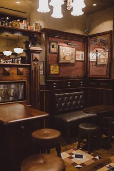 the interior of a bar with stools, tables and pictures hanging on the wall