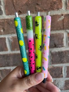 four different colored lighters are held up in front of a brick wall with yellow and green confetti on them