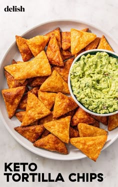 a white plate topped with tortilla chips and guacamole