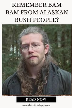 a man with long hair and glasses is looking at the camera in front of trees