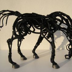 a sculpture of a horse made out of metal pipes and wires on a white surface