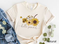 Hello summer T-shirt with cute sunflowers! Perfect summer T-shirt for you or great T-shirt gift for your family, friends, co-workers who love sunflower. This classic unisex jersey short sleeve tee fits like a well-loved favorite. Soft cotton and quality print make users fall in love with it over and over again. These t-shirts have-ribbed knit collars to bolster shaping. The shoulders have taping for better fit over time. Dual side seams hold the garment's shape for longer.  .: 100% Airlume combe Yellow T-shirt With Sunflower Design For Spring, Summer Casual T-shirt With Sunflower Print, Yellow Vacation T-shirt For Spring, White Summer Top With Sunflower Print, Yellow Spring Vacation T-shirt, Yellow Plant Print Summer Top, Summer Sunflower Design Short Sleeve T-shirt, Yellow T-shirt With Plant Print For Summer, White T-shirt With Sunflower Print For Spring