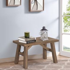 a small wooden table with two pictures on the wall above it and a candle next to it