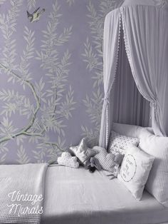 a white bed sitting next to a purple wall with a bird on it's head