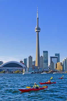 several kayakers are in the water near a large city with tall buildings and a sky scraper