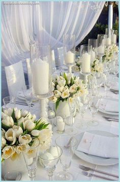 a long table is set with white flowers and candles for a formal dinner or reception