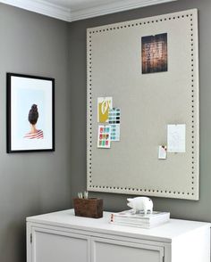 a white dresser topped with lots of clutter next to a wall mounted art piece