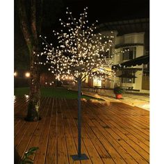 a tree with white lights on it in the middle of a wooden deck at night