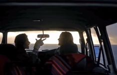 two women sitting in the back seat of a car looking at each other and talking