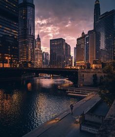 the city skyline is lit up at night with skyscrapers and boats on the water