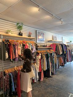 a woman looking at clothes on racks in a clothing store