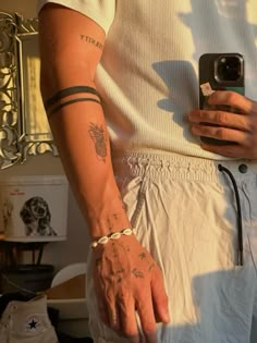 a man with tattoos on his arm is holding a cell phone and wearing white shorts