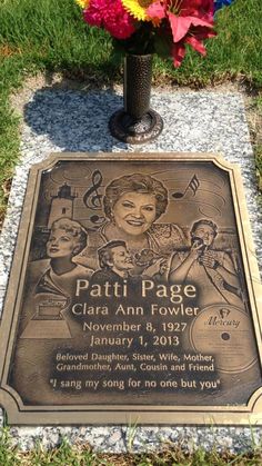 a plaque on the ground with flowers in front of it that reads patti page cia ann power