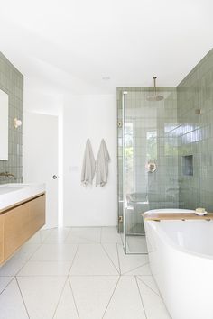 a bathroom with a tub, sink and mirror in it's center wall is shown