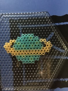 a beaded object sitting on top of a glass table next to a blue wall