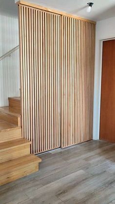 an empty room with stairs and wooden slats on the wall, next to a sliding door