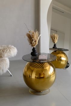 two golden vases sitting on top of metal tables