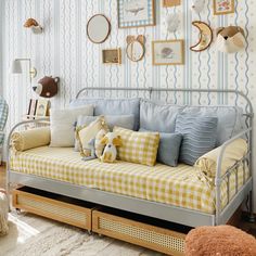 a day bed with pillows and stuffed animals on it in a room decorated with wallpaper