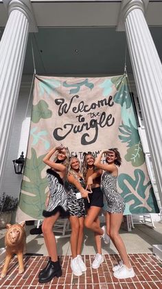 three girls standing in front of a welcome to jungle banner