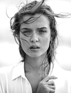 a black and white photo of a woman with her hair blowing in the wind