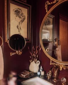 a bathroom sink sitting under a mirror next to a wall mounted faucet and framed pictures