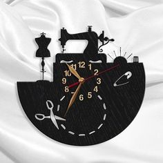 a clock that is on the side of a white sheet with scissors and sewing machine