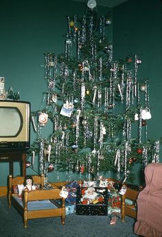 a christmas tree with ornaments hanging from it's branches in front of a tv