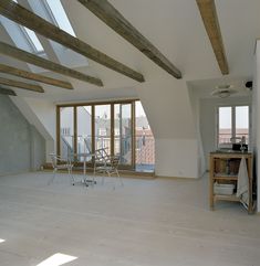 an empty room with large windows and wooden beams on the ceiling is pictured in this image