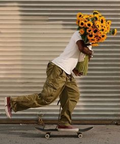 a man riding a skateboard down a street holding flowers on top of his head