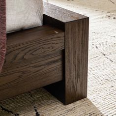 a wooden bench sitting on top of a carpeted floor next to a bed frame