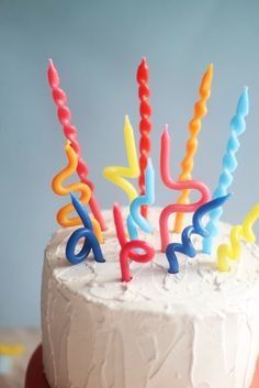 a birthday cake with white frosting and colorful candles