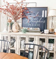 a dining room table with chairs and a sign on the wall above it that says autumn leaves and pumpkin please