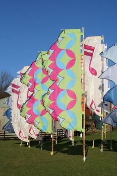 several large colorful kites on poles in the grass