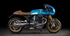 a blue motorcycle parked on top of a cement floor next to a black background with yellow accents